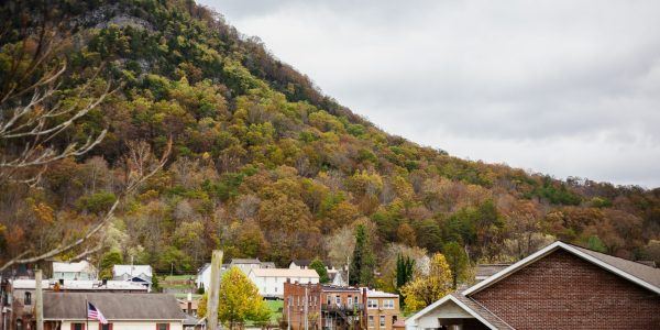 An Appalachian town with a variety of houses and buildings. There is a fall mountain scape in the distance.