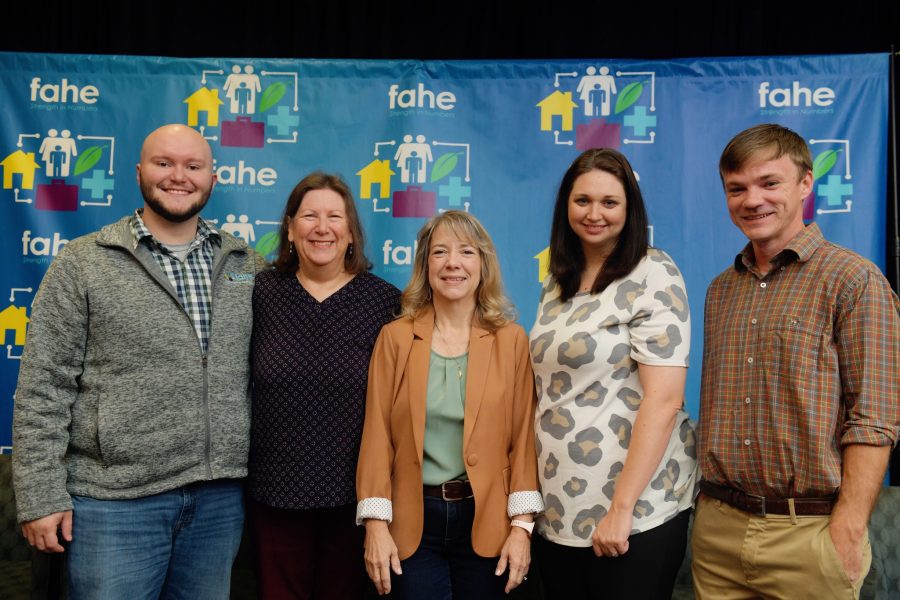 A group of five Fahe members are standing in front of a step-and-repeat backdrop at an annual event.
