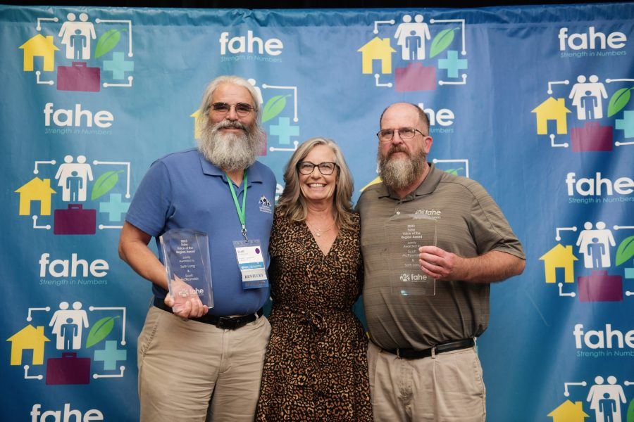 A group of three Fahe members are standing in front of a step-and-repeat backdrop smiling. Two of the members are holding awards.